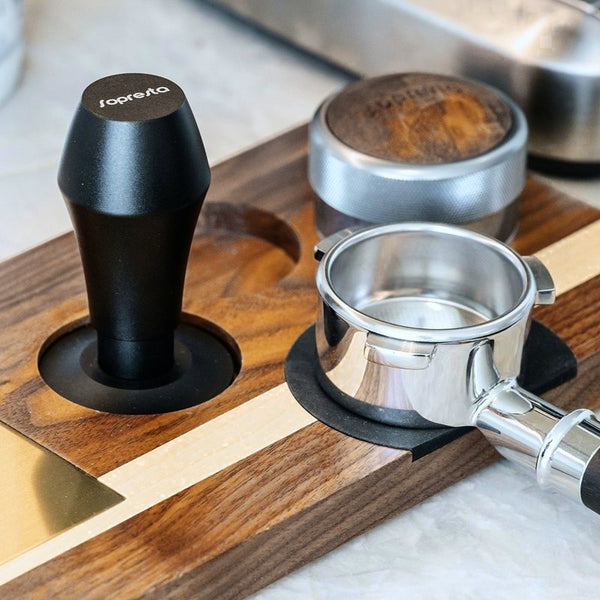 Sopresta-tamper, fordeler og portafilter på en tamperstation i valnød
