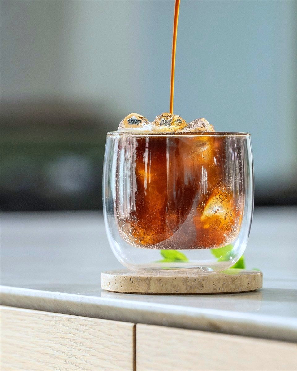 Espresso tonic: espresso løber ned over is i et dobbeltvægget glas