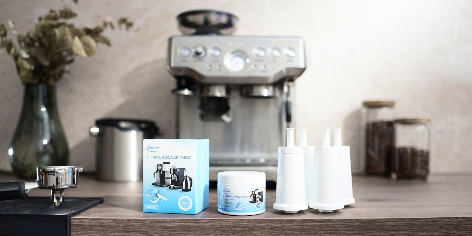 En espressomaskine med Pure Wave-vandfiltre, Puritex rense- og afkalkningstabletter, et portafilter på tampermåtten og kaffebønner i glas