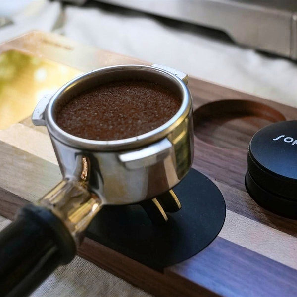 Et portafilter med kaffe ved en Sopresta-tampermåtte