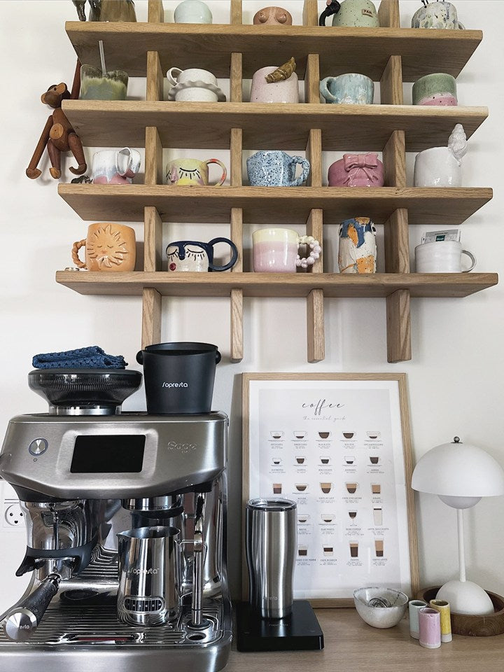 Et kaffehjørne med en Sage-espressomaskine under hylder med kopper